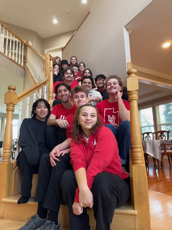 Salt Flats members in red University of Utah shirts on a staircase at retreat