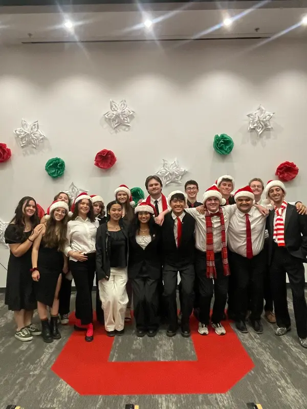 Salt Flats A Cappella in Santa hats at the winter concert, standing on the block U